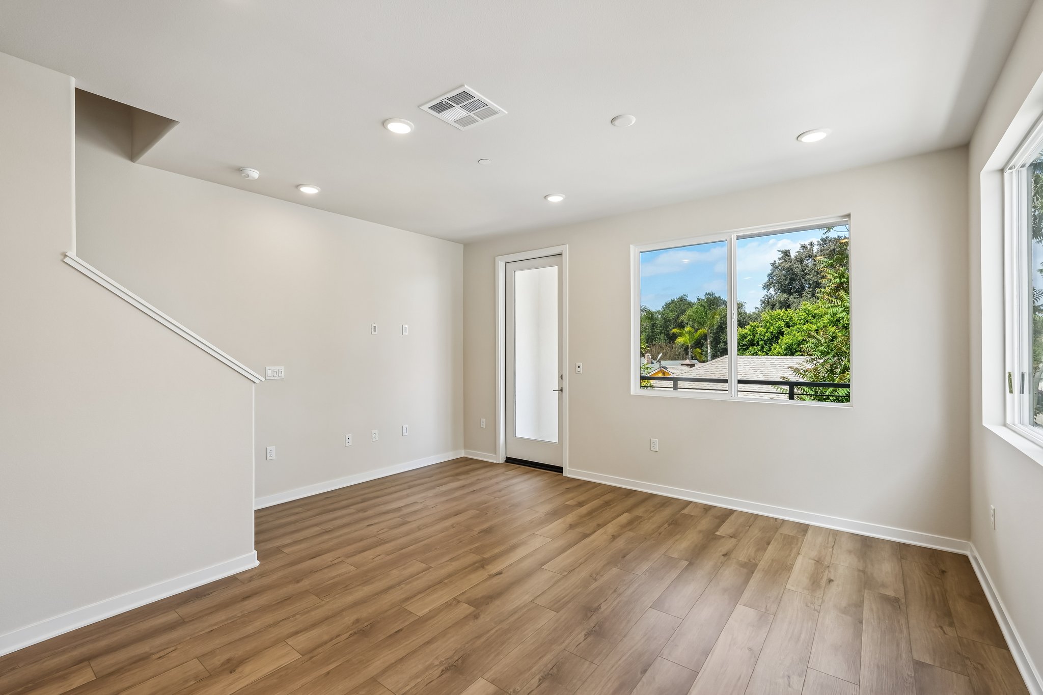 A room with a wood floor and a window with a view of the trees.