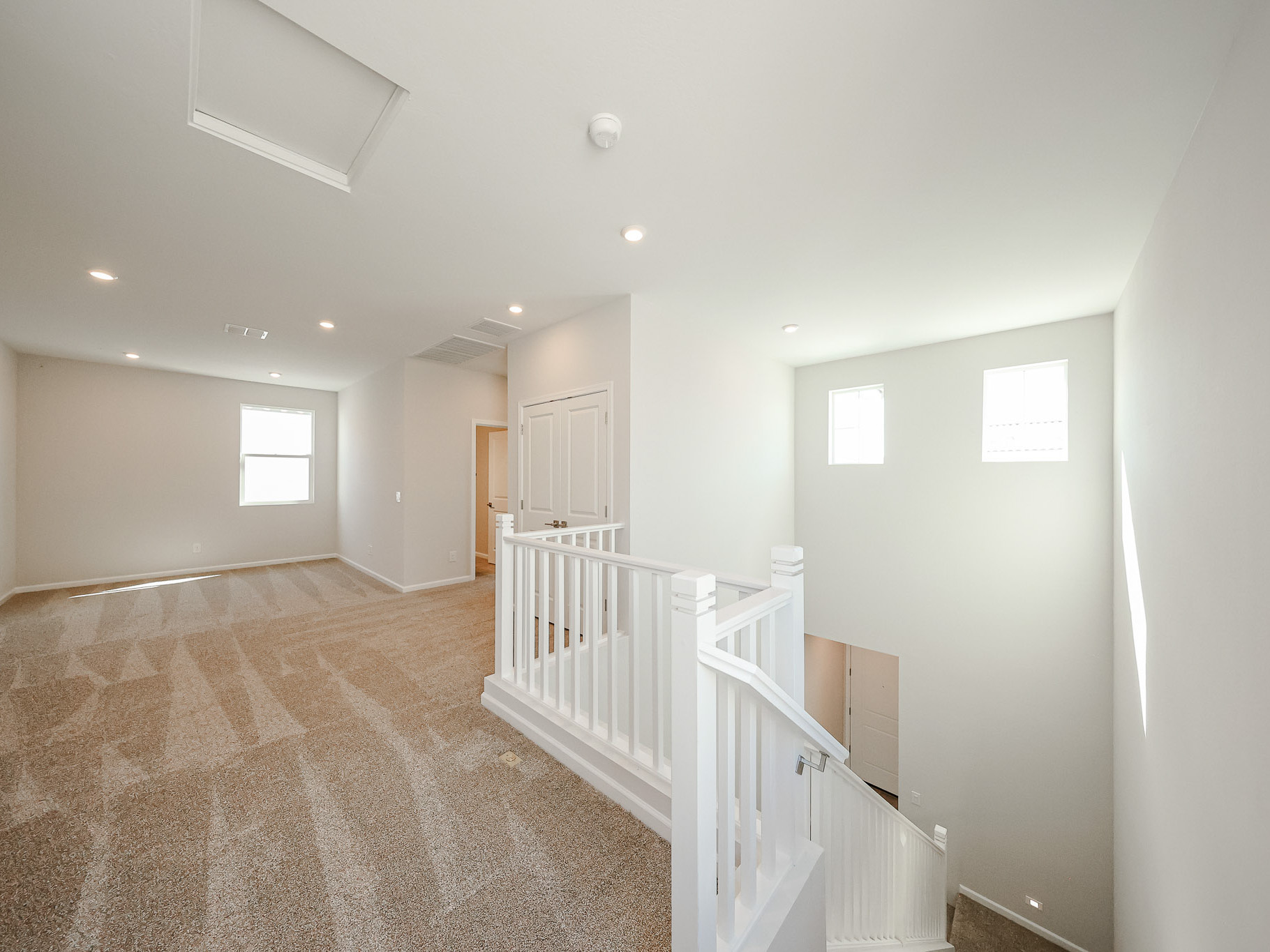 A room with white railings and a white staircase.