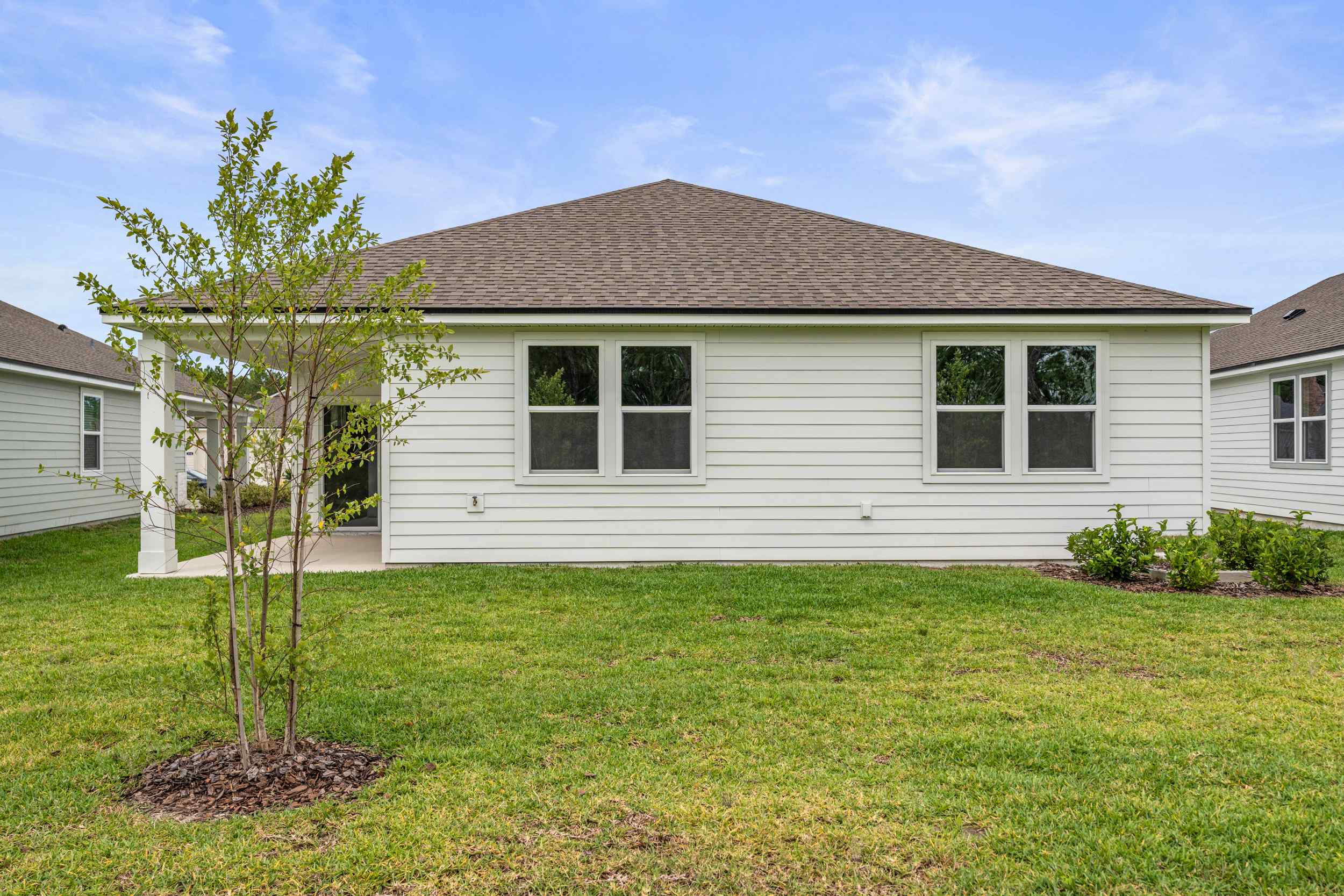 Palmetto Floorplan Lot 145 Backyard with Tree and Covered Patio at Seminole Palms in Palm Coast