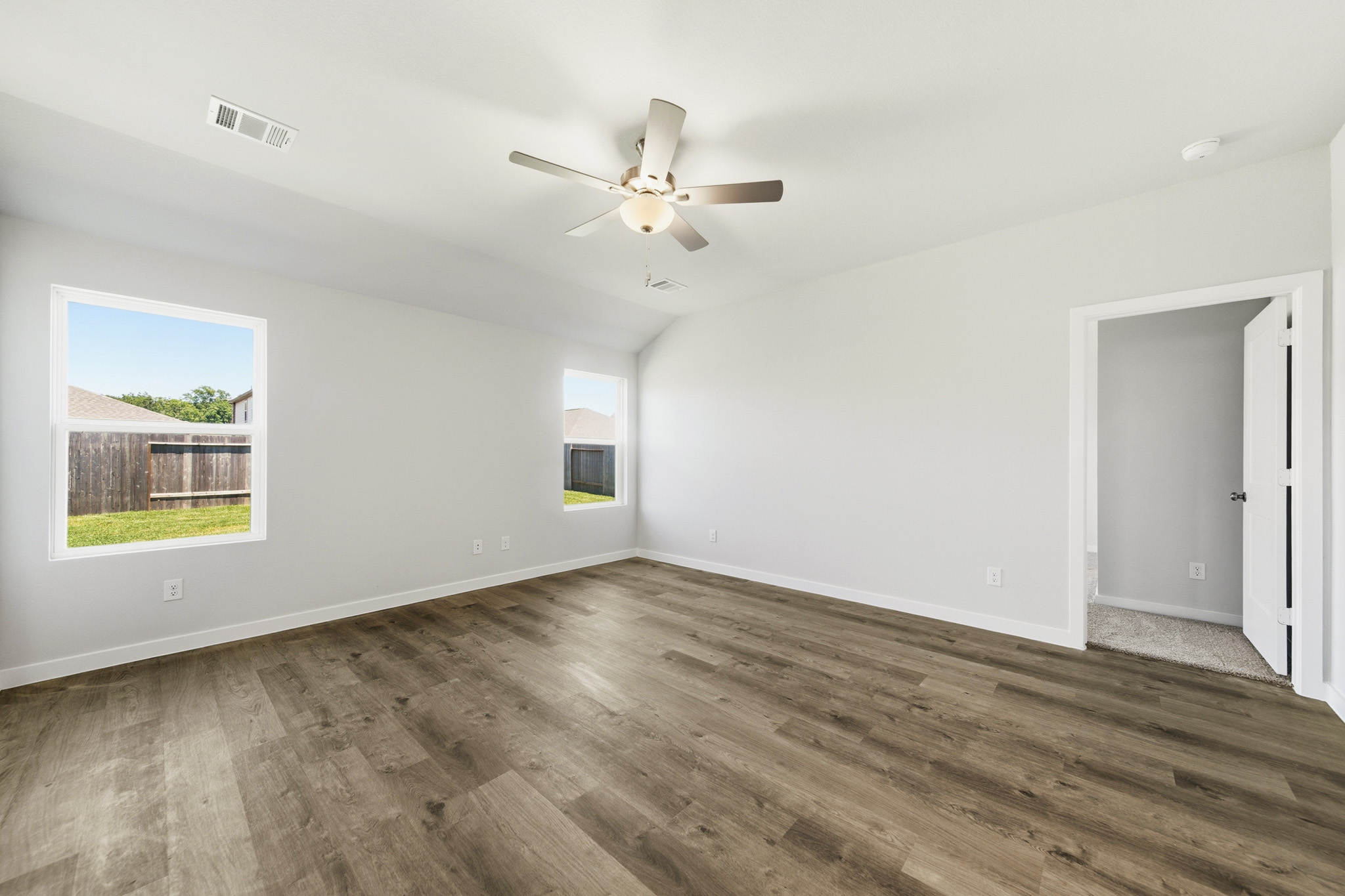 A room with a ceiling fan and a wood floor.