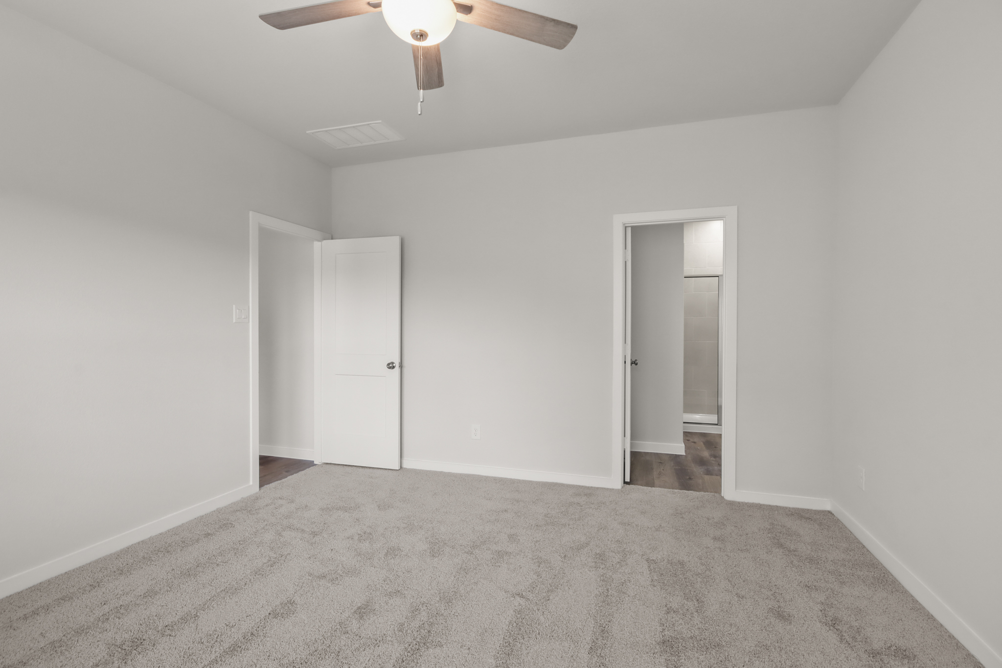 A room with a ceiling fan and a door.