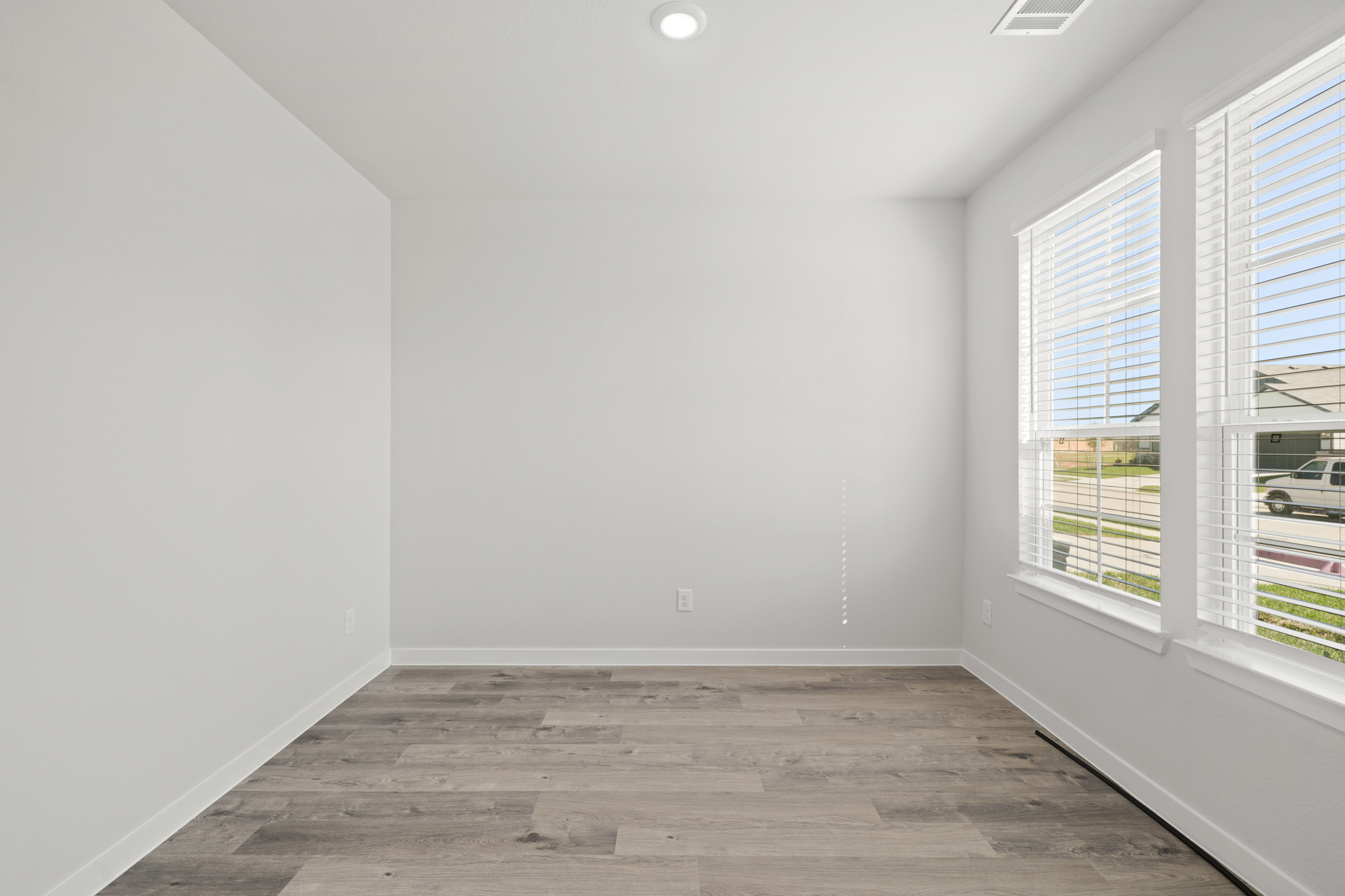 A room with windows and a wood floor.