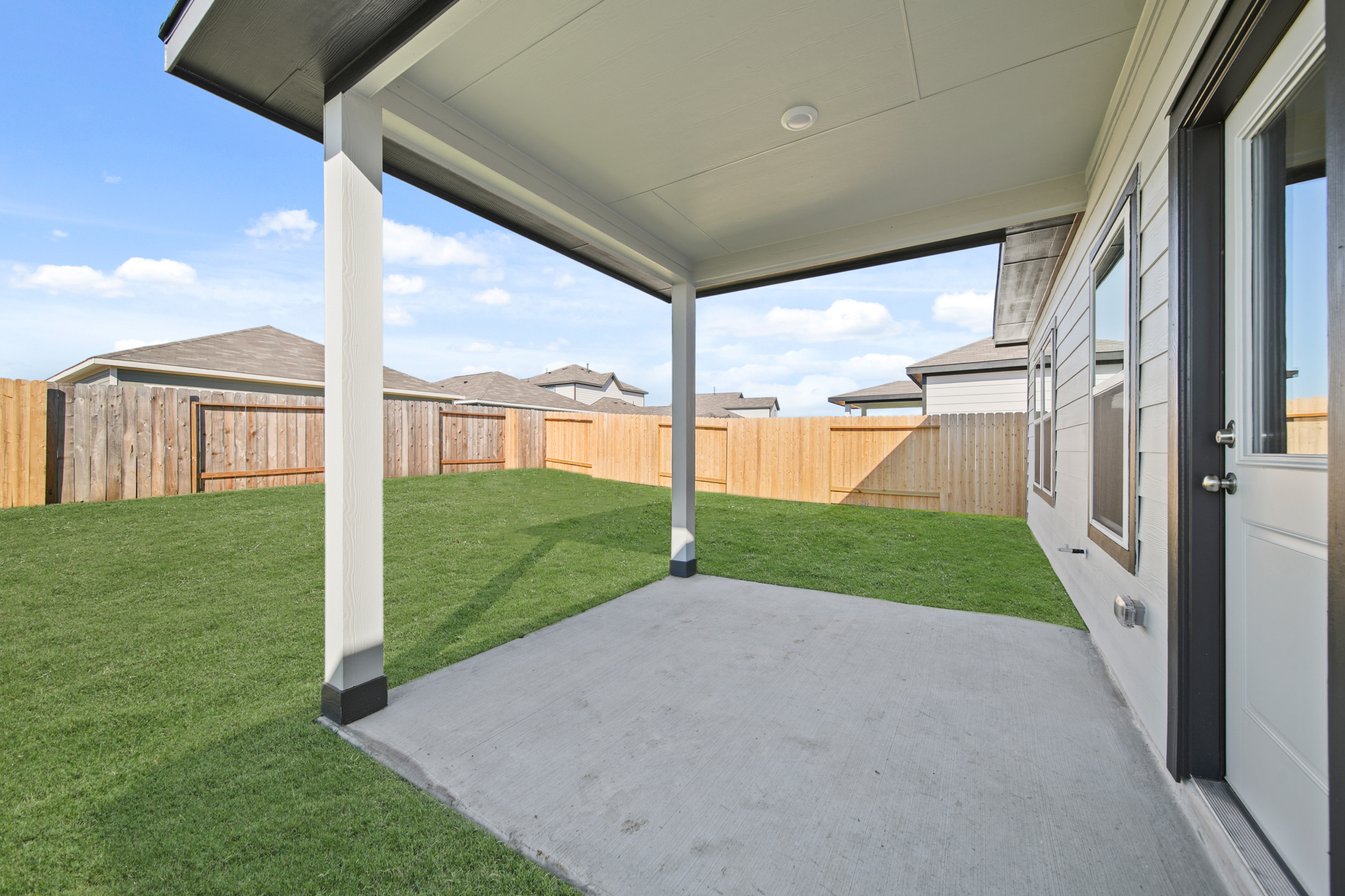A backyard with a fence and a grass yard.