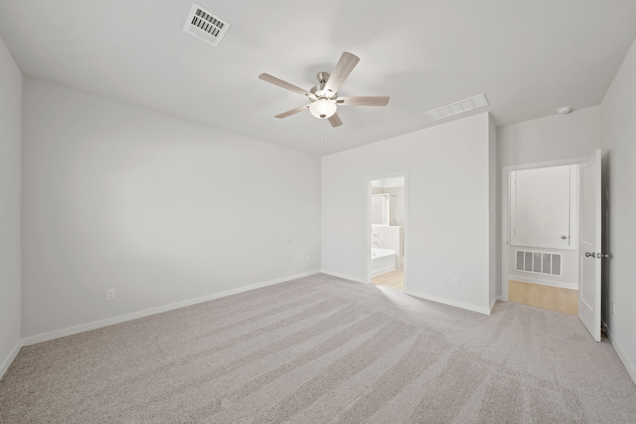 A room with a ceiling fan and a carpet.