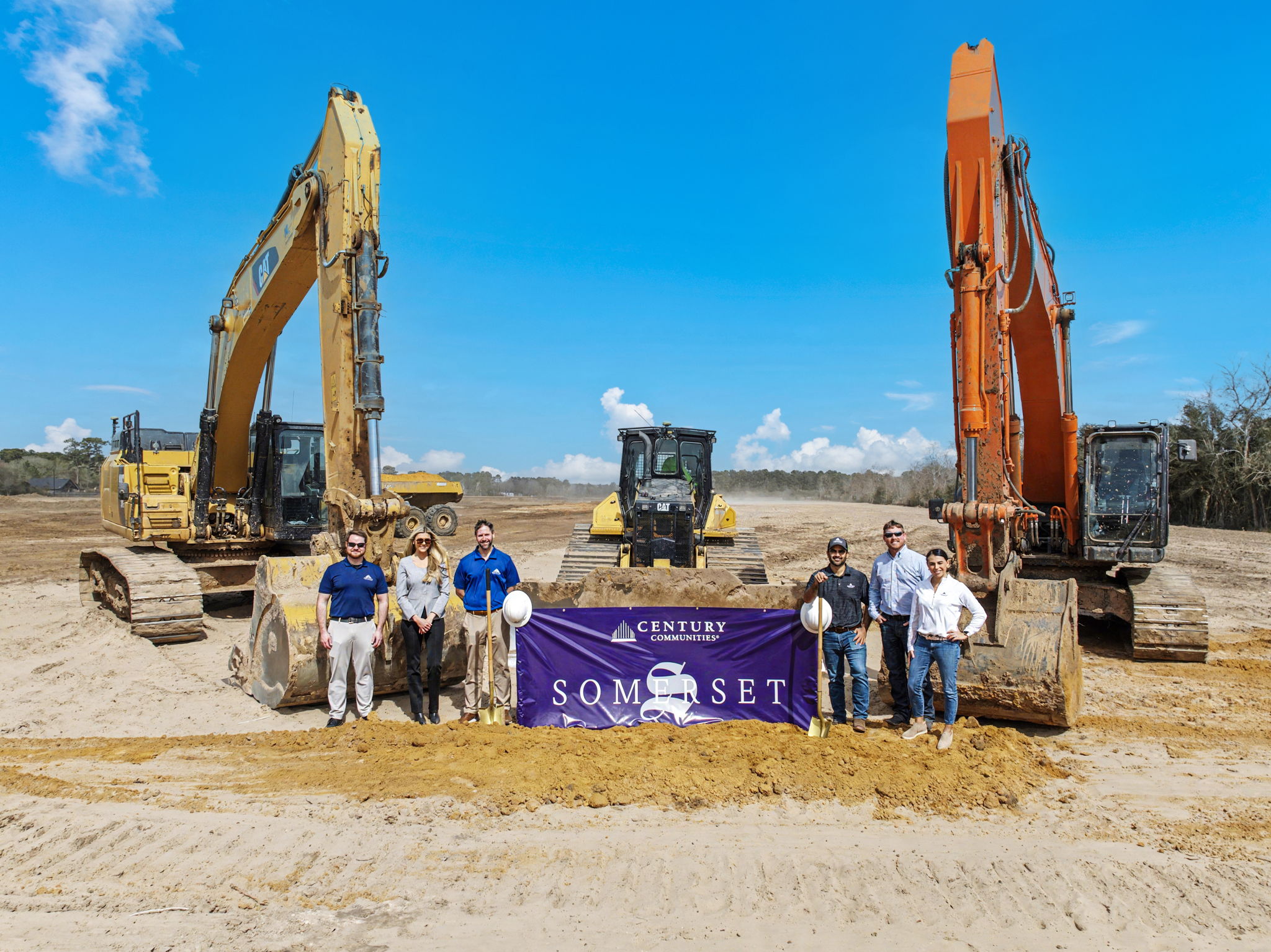 A group of people standing next to a construction vehicle.