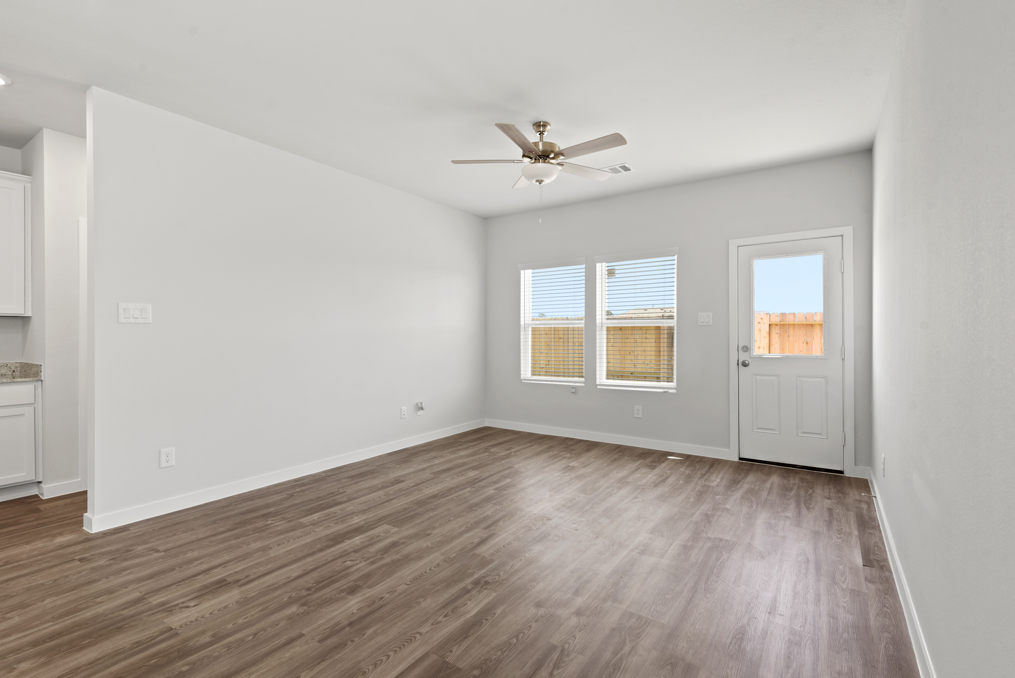 A room with a wood floor and a ceiling fan.