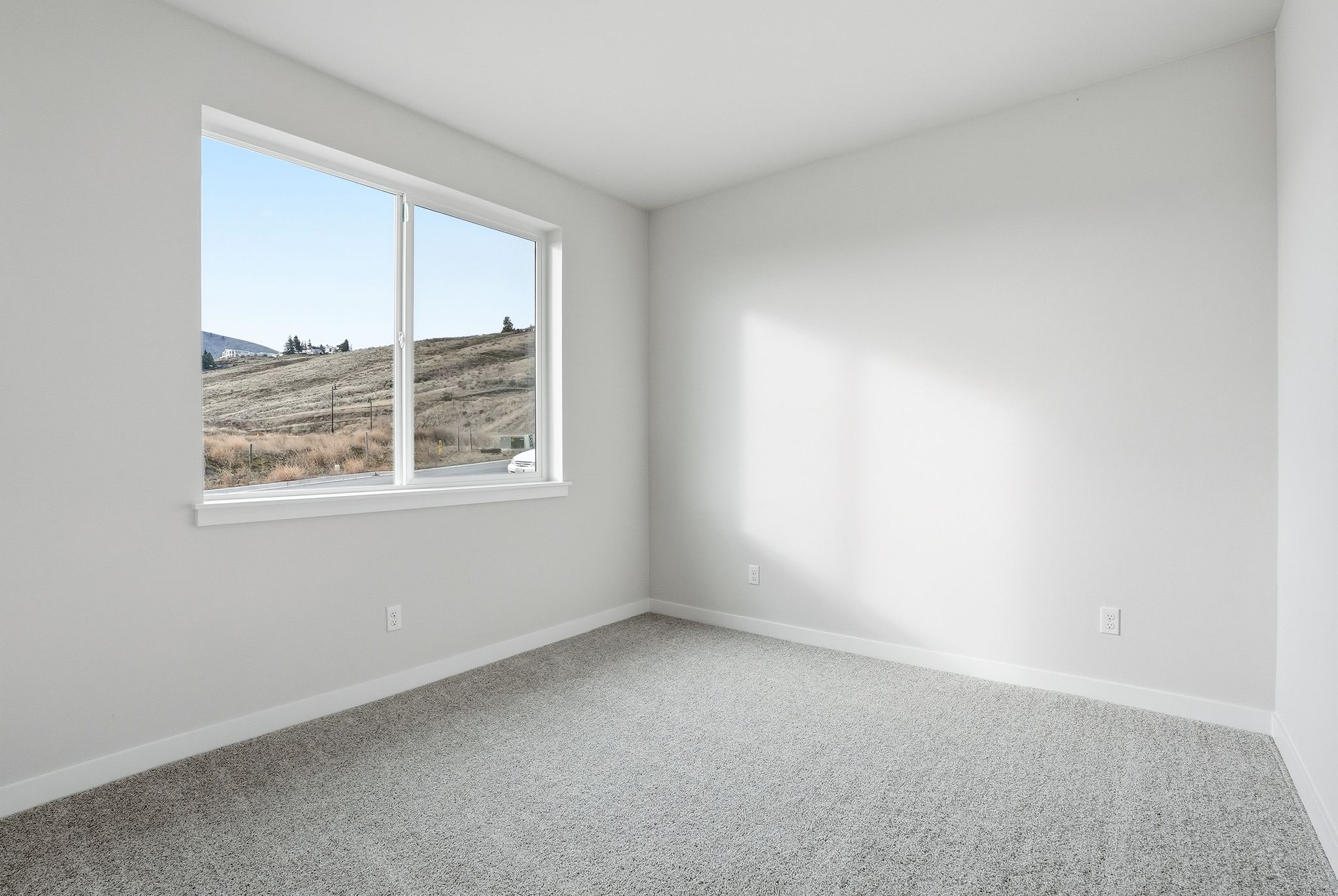A room with a window and a view of a field.