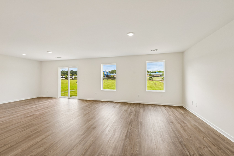 A room with a wood floor and a wood floor with a few paintings on the wall.